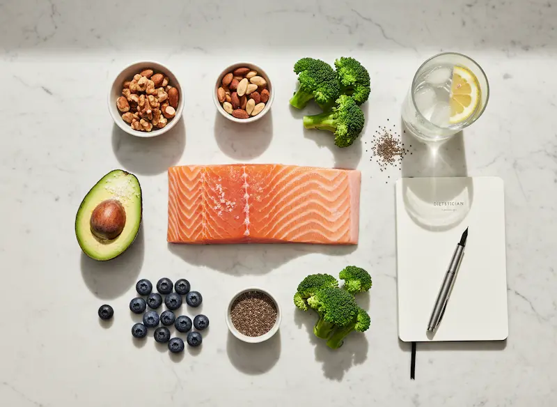 Guide des Régimes 2026 : Optimisation des macronutriments et santé durable Composition équilibrée d'aliments bruts (saumon, avocat, baies, noix) sur une table en bois clair, illustrant un régime alimentaire à haute densité micronutritionnelle